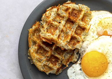 Waffle-iron hash browns on a plate with sunny side up eggs.