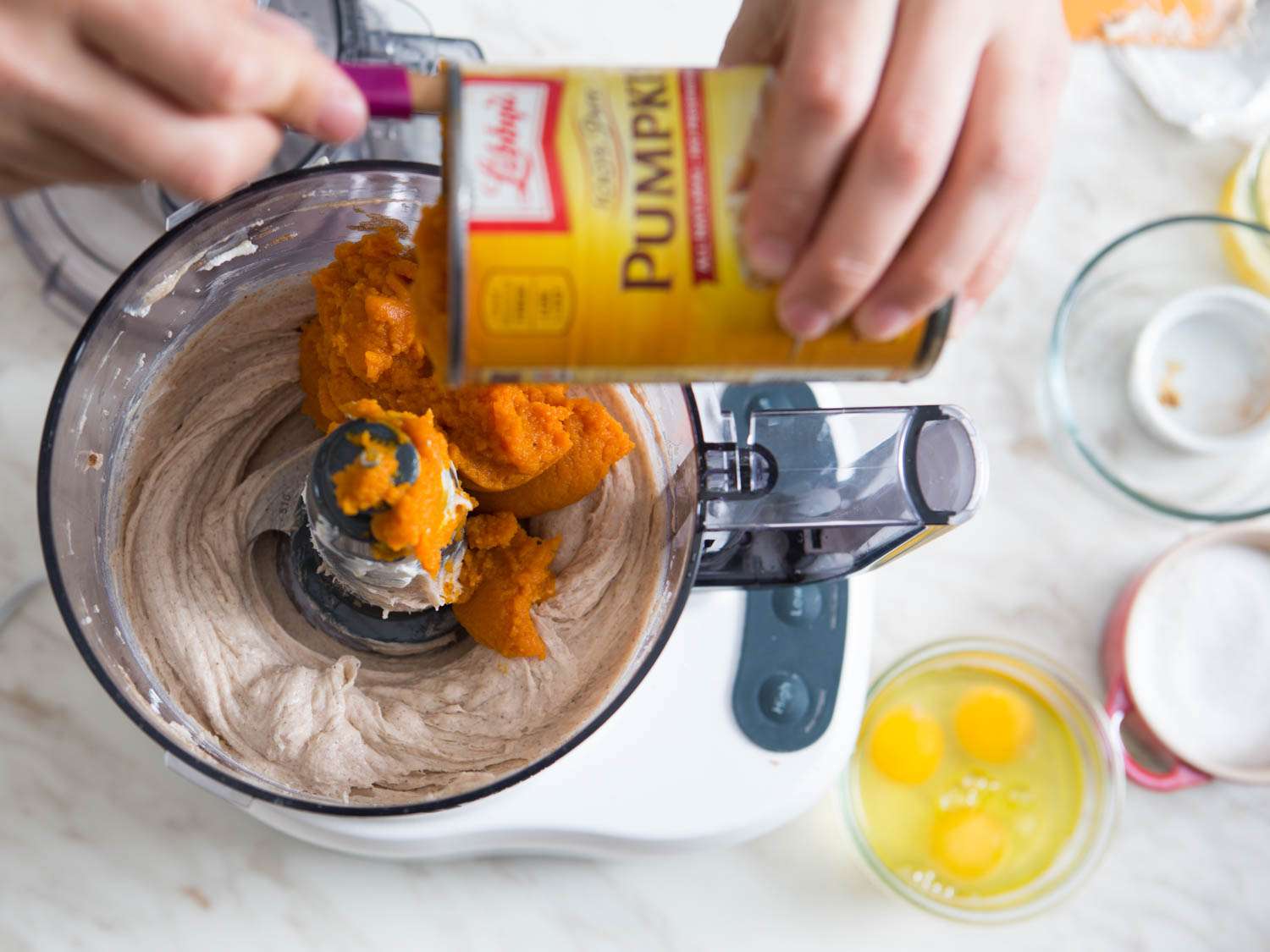 Adding pumpkin puree to a food processor. 