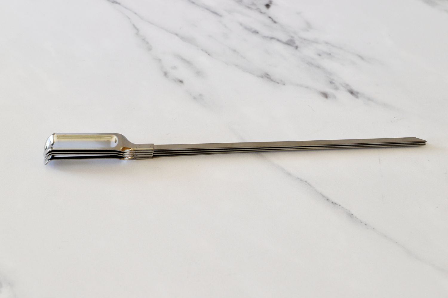The OXO skewers on a marble kitchen countertop.