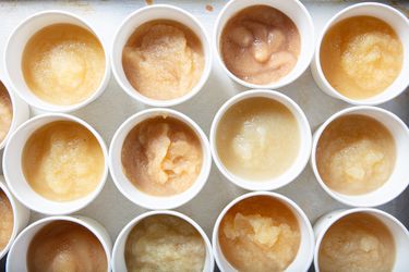 Assorted cups of applesauce displayed in rows on a surface