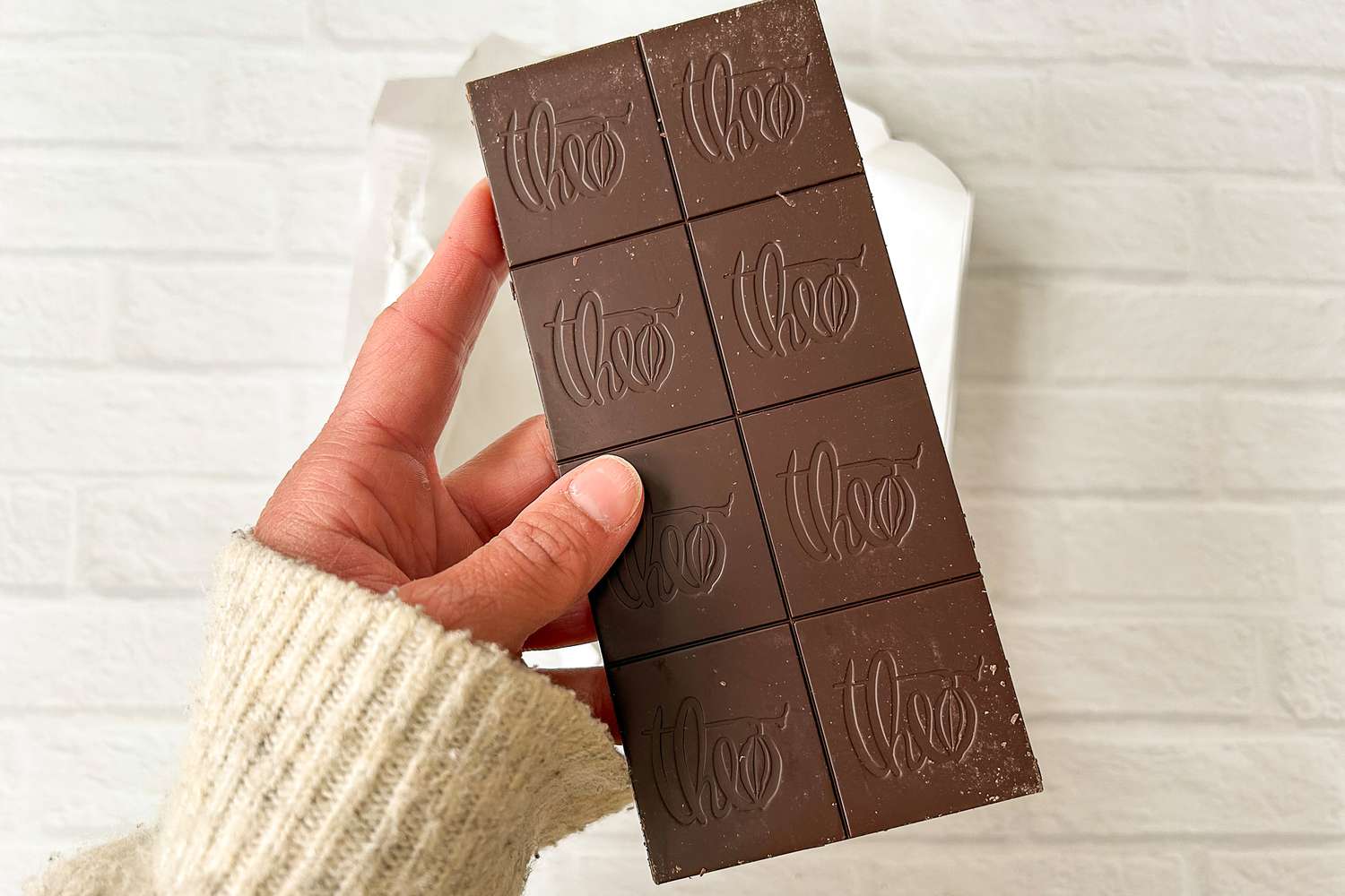  A hand holding the Theo Pure Dark 85% Chocolate Bar