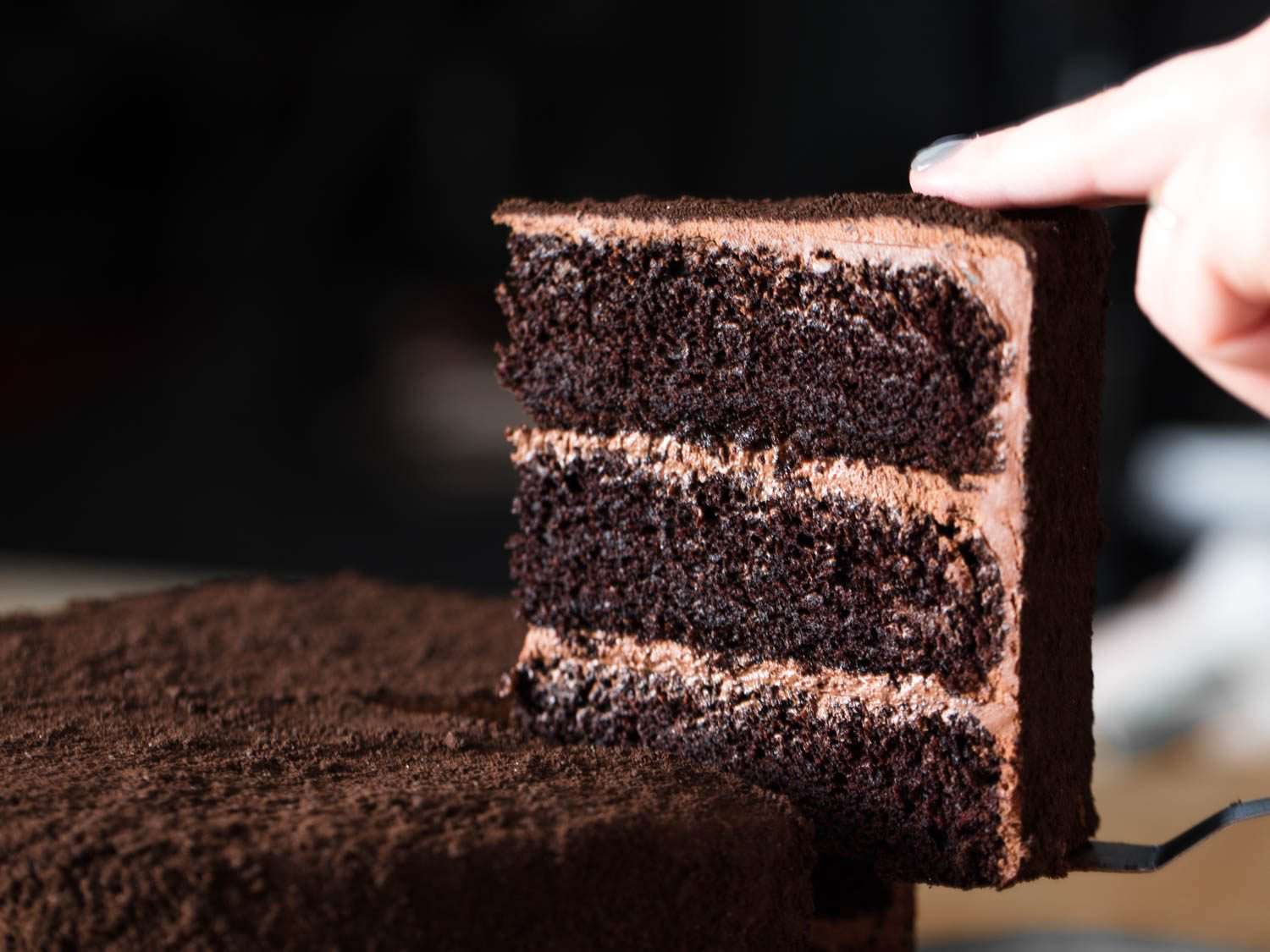 Pulling out a slice of three-layer chocolate Devil's food cake.
