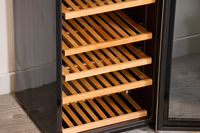 A wine fridge's empty, wooden racks.