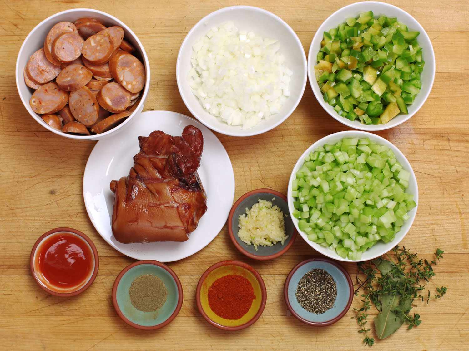Bowls holding various ingredients for New Orleans–style red beans and rice.