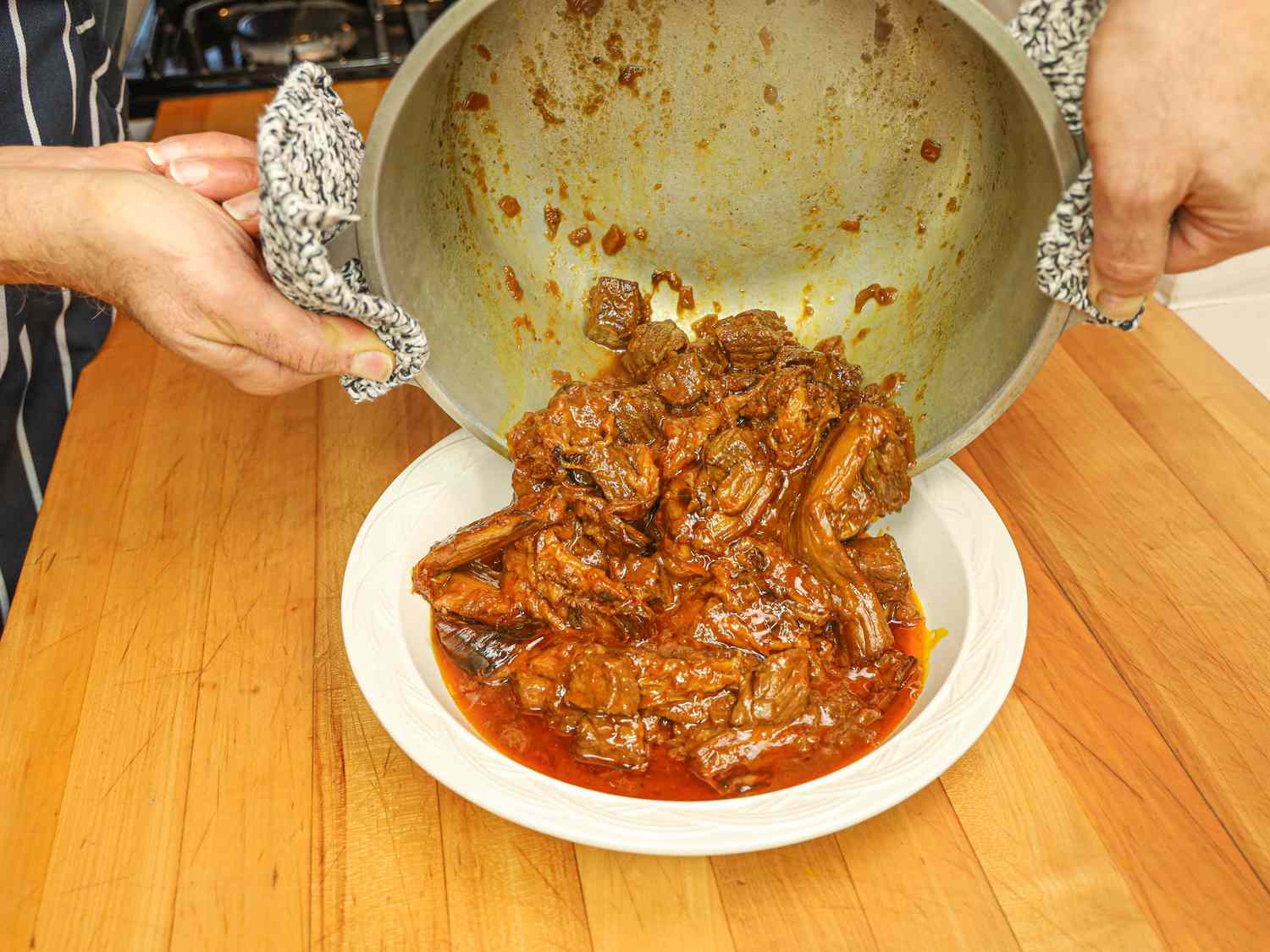 Side view of dumping stew into a bowl from pot