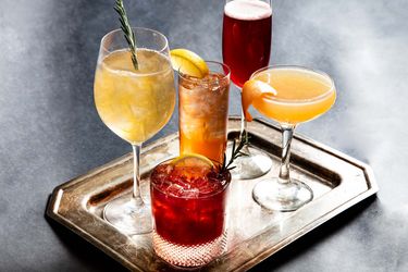 A tray with five glasses holding five different holiday cocktails
