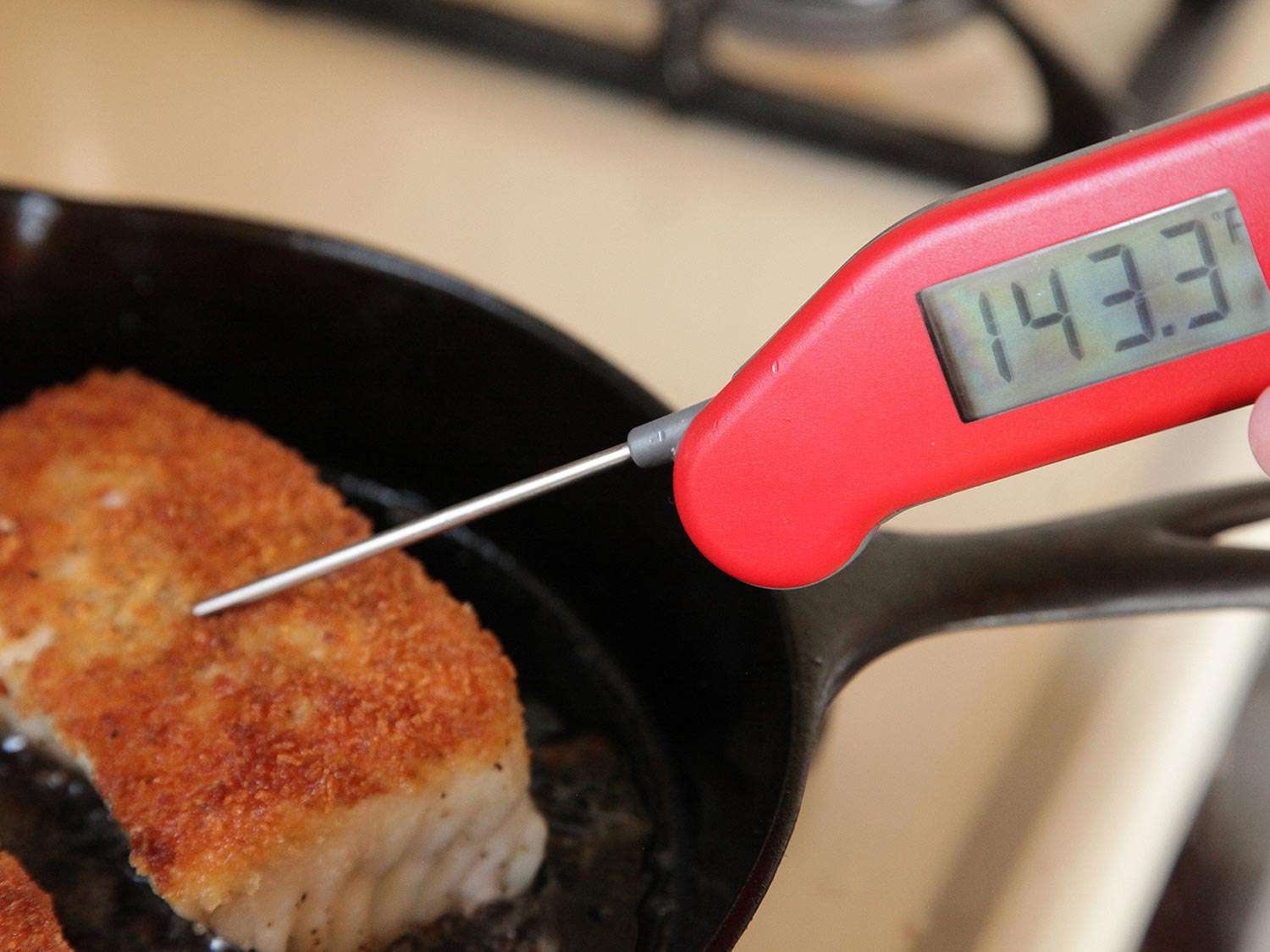 A digital thermometer checks the internal temperature of the fish. (Reading 143.3 degrees Fahrenheit.)
