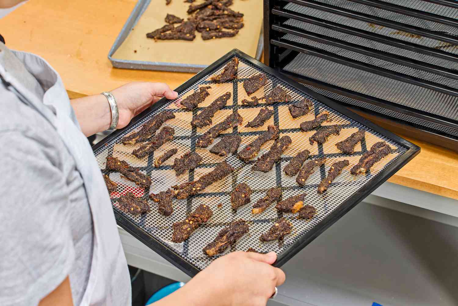 A person holding the Excalibur Electric Food Dehydrator Machine food tray