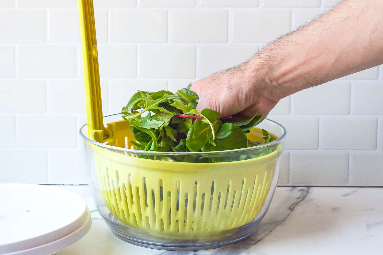 a person placing greens in the chef'n salad spinner