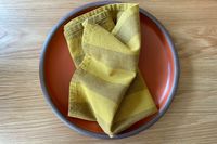 Yellow stripe cloth napkin on top of a orange plate