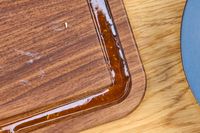 Closeup of a Virginia Boys Kitchens Walnut Wood Cutting Board with a grove partially filled with sauce or liquid