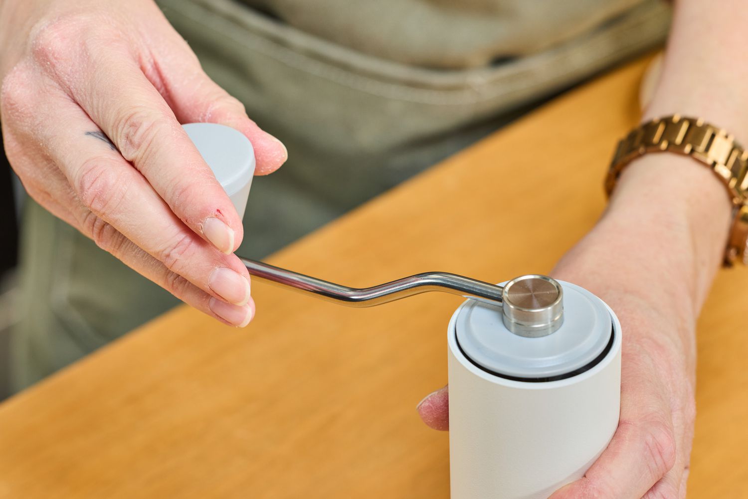 A person turns the crank on the top of the Timemore C2 Max Manual Grinder