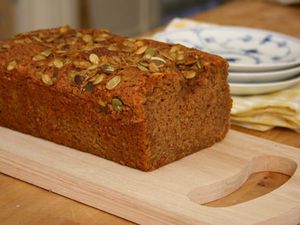 A loaf of pumpkin tea cake on a wood cutting board. 