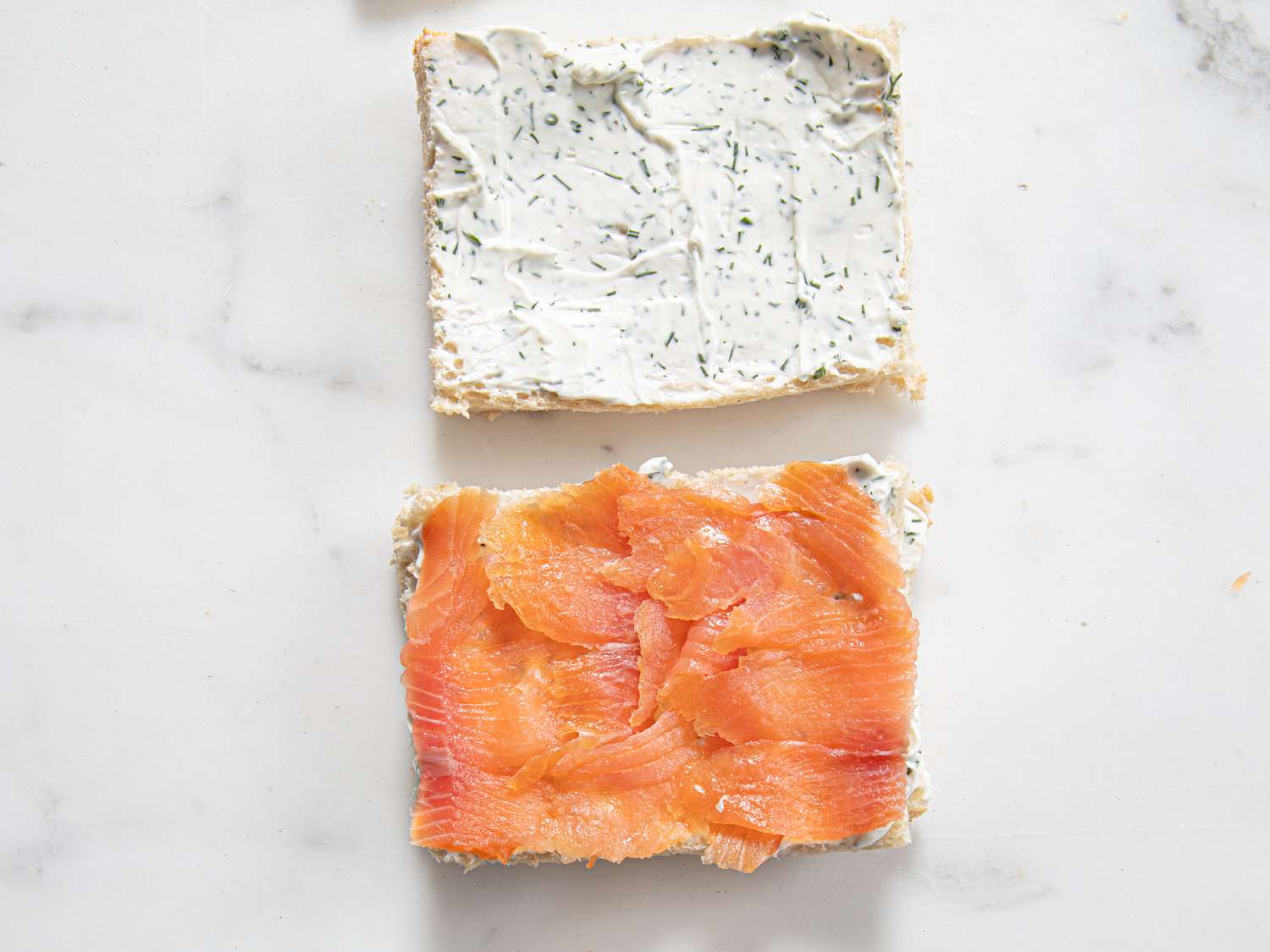 Overhead view of cream cheese and salmon added to sandwich