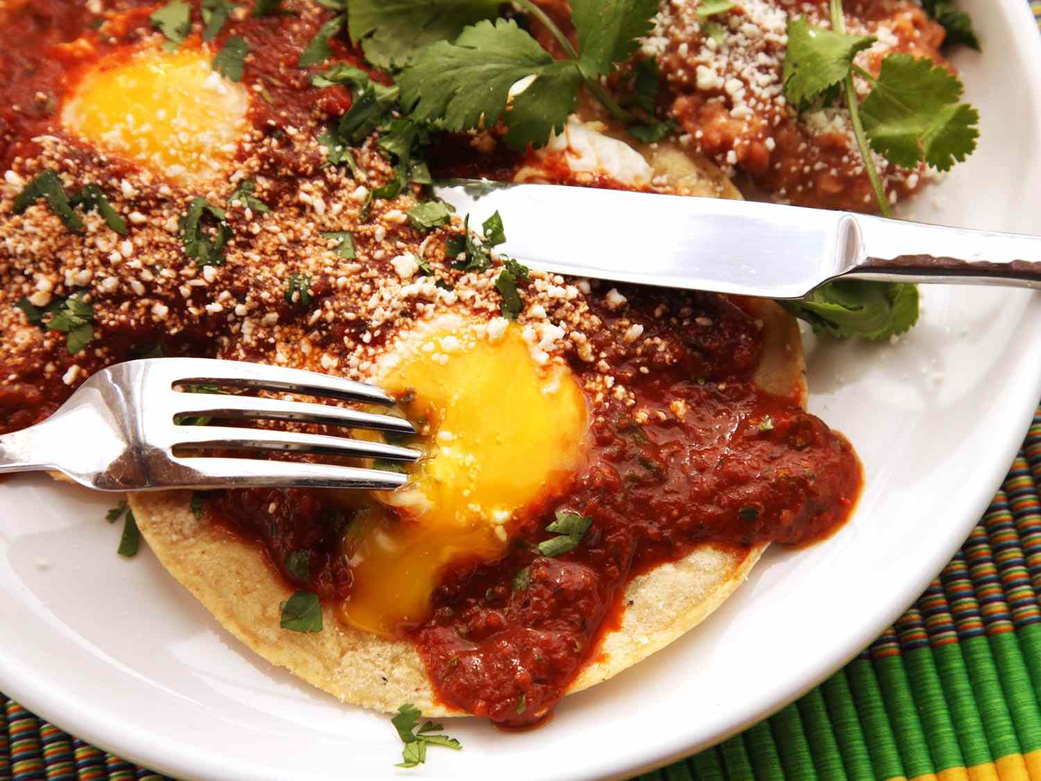 A plate of spicy homemade huevos rancheros with tomato chile salsa.