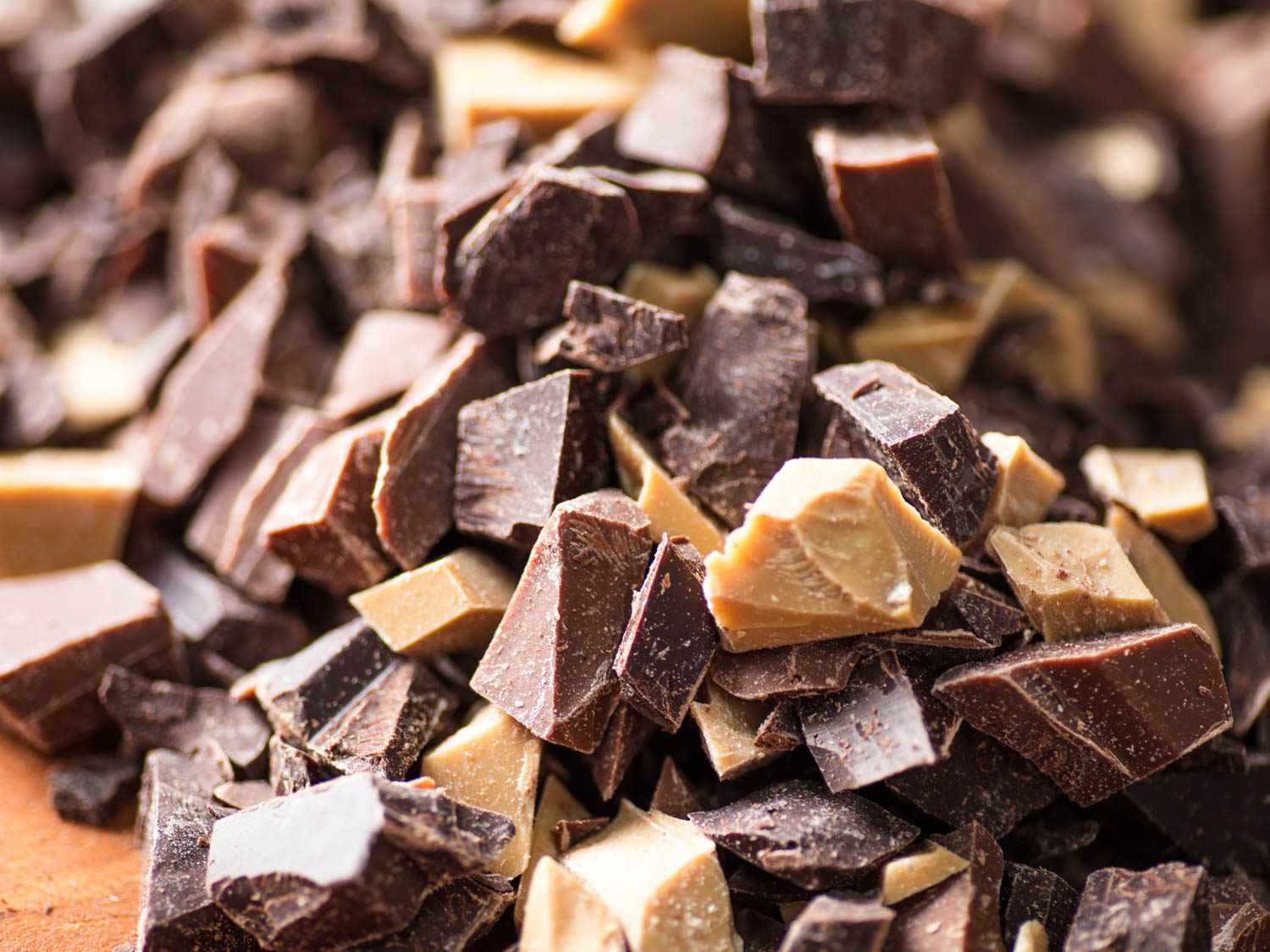 A pile of roughly chopped chocolate, including dark, milk, and white varieties.