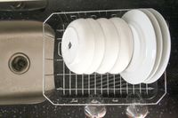 The Rubbermaid dish rack drying plates and bowls next to a kitchen sink.