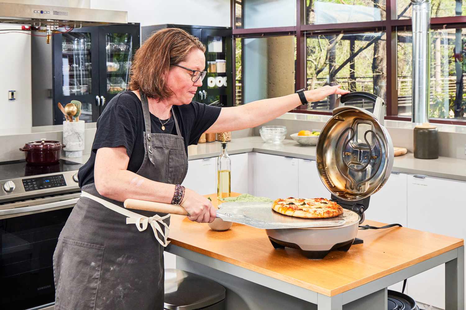 A person retrieving a pizza with a pizza peel from the Breville pizza maker.