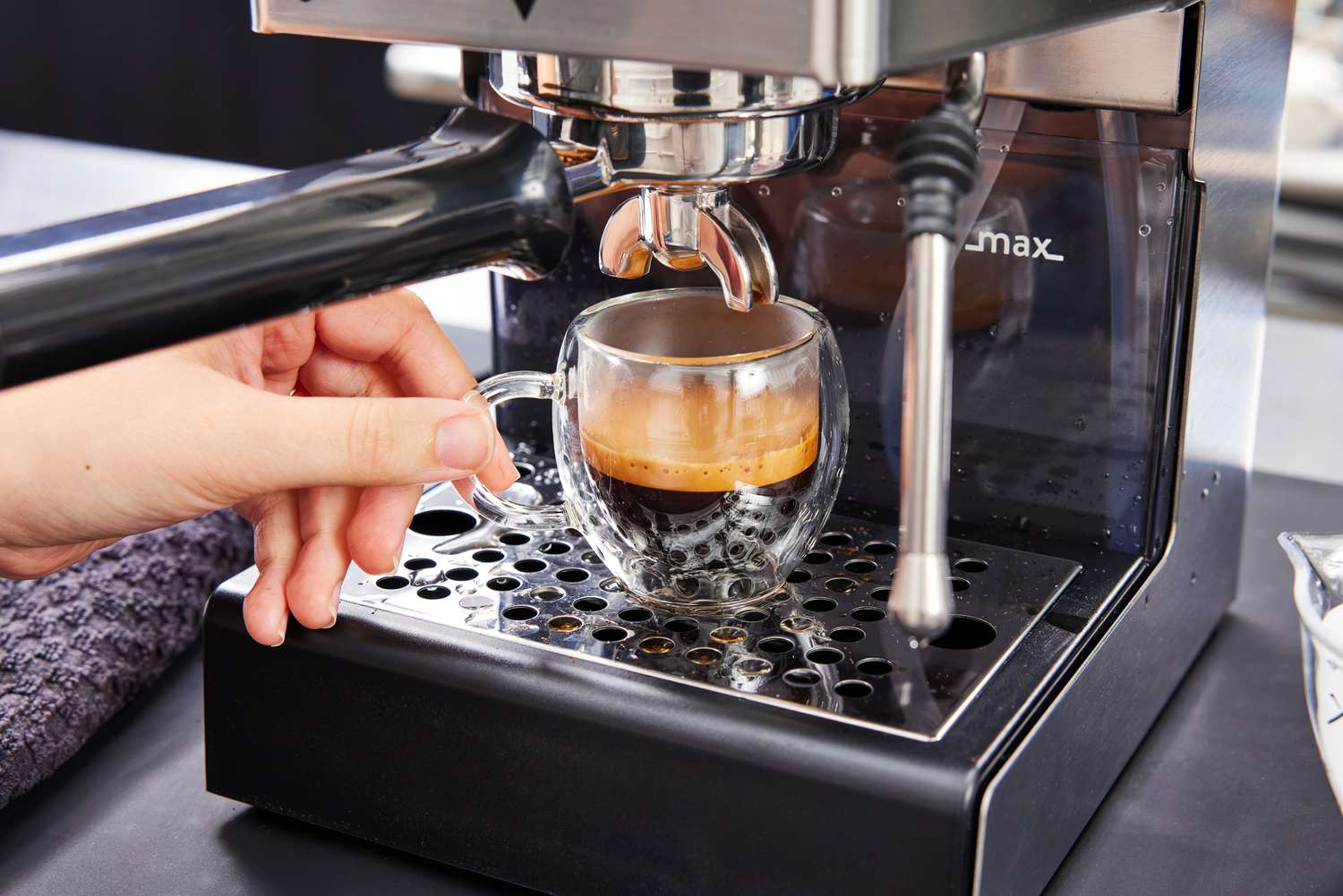 Hand adjusting a filled espresso cup on the base of the Gaggia Classic Pro Espresso Machine