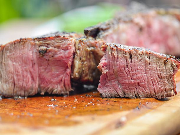 Close-up of a cooked porterhouse that's been cut open. It is rosy-red and has a soft center, with not too much grayness around the edges.