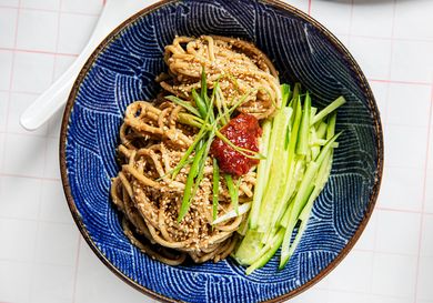 Sesame Noodles with chili paste, cucumbers, and scallions in a blue bow with a wavy patterm