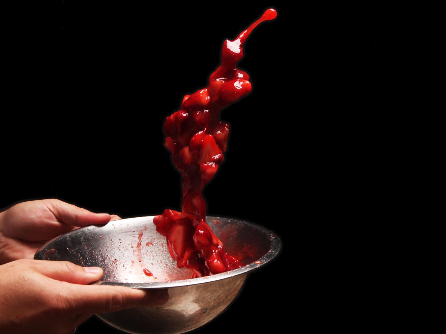 Tossing macerated strawberries into the air from their bowl.
