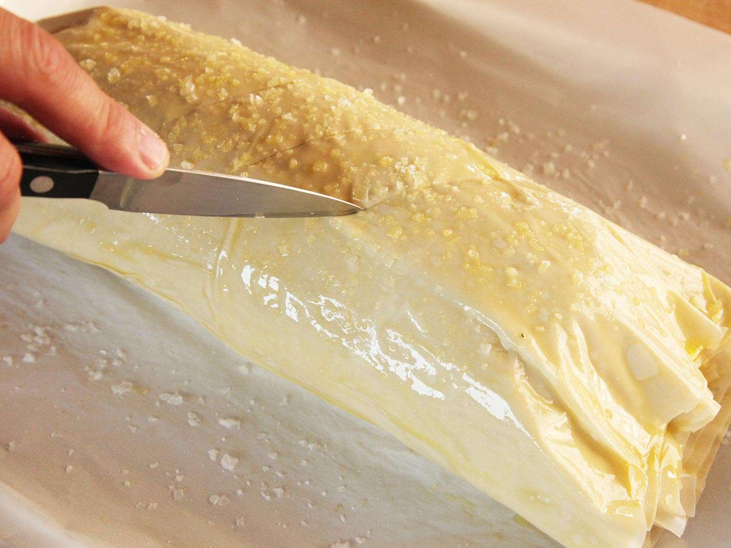 Scoring olive oil coated roast with a small knife.