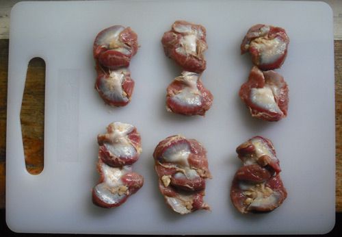 Raw chicken gizzards resting on a cutting board