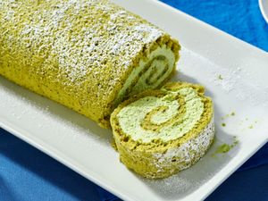 Matcha Swiss roll on a white plate sliced to show the spiraled filling