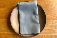 A napkin folded on a plate placed on a wooden table