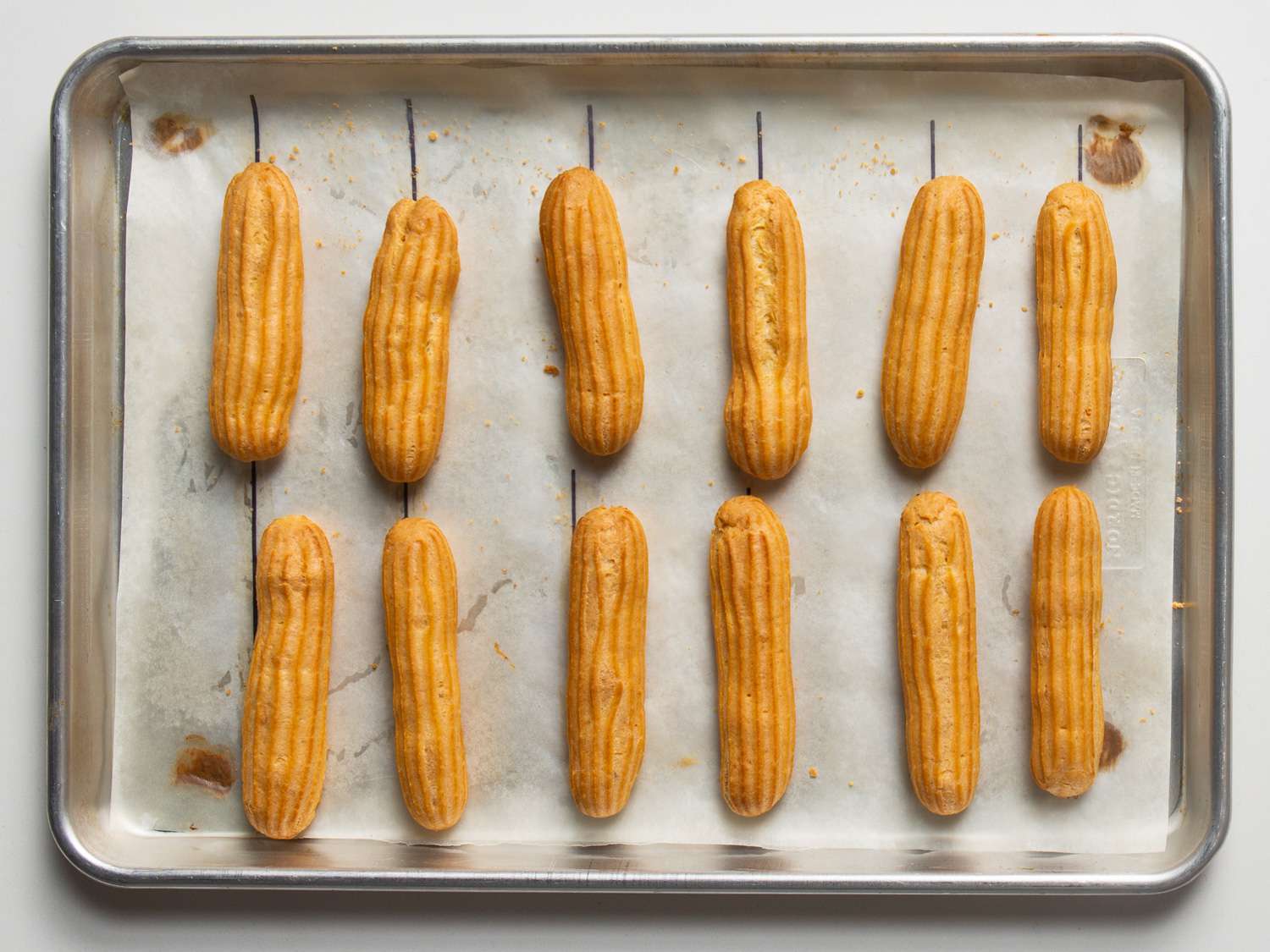 Overhead of rows of baked éclairs on a baking sheet.
