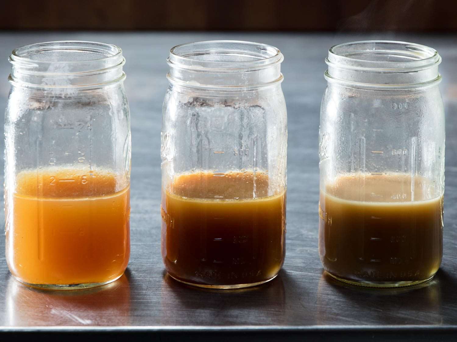 Three jars of chicken stock made using varying methods.
