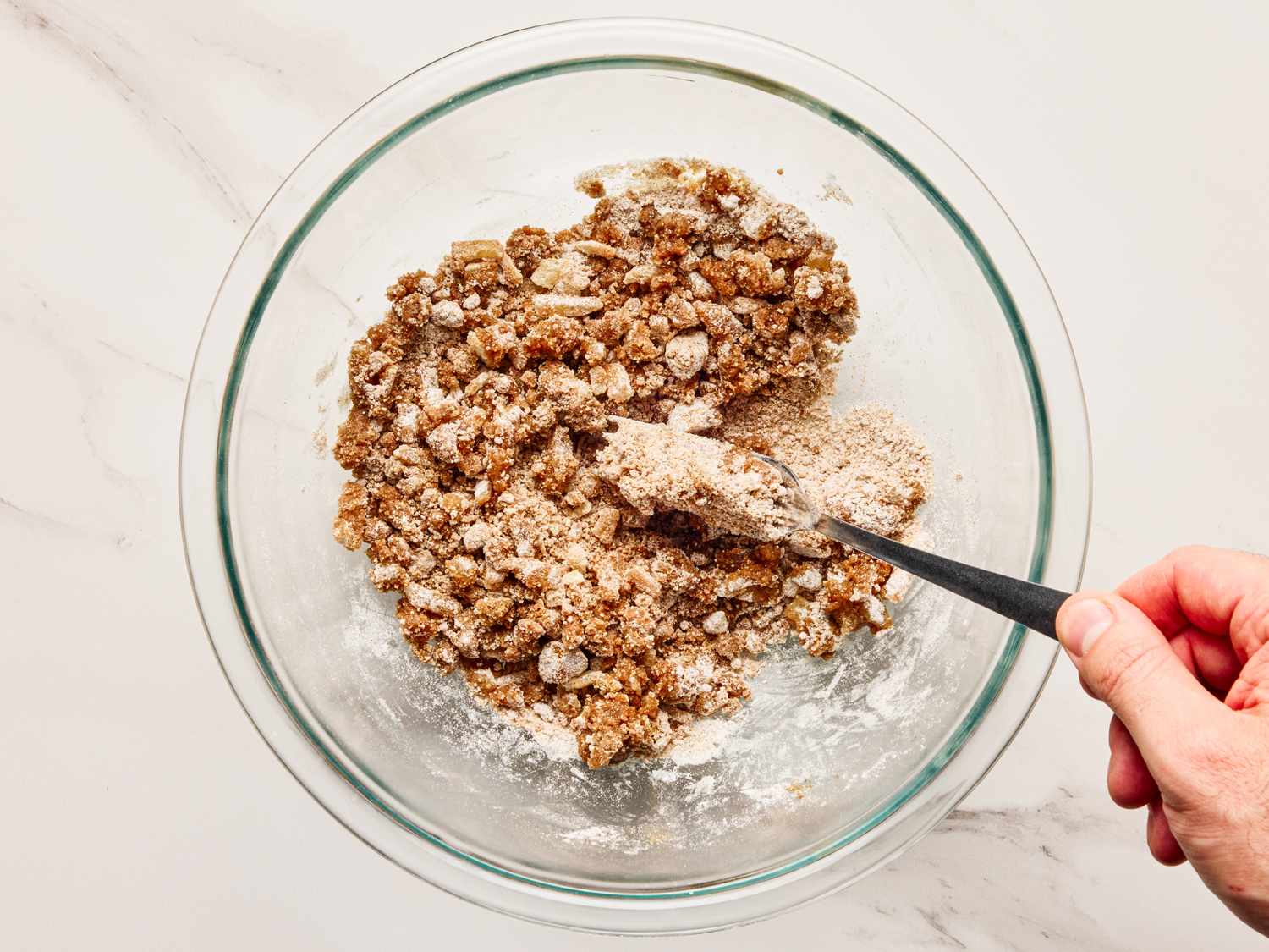 Hand mixing spiced gingerbread muffin ingredients in a glass bowl