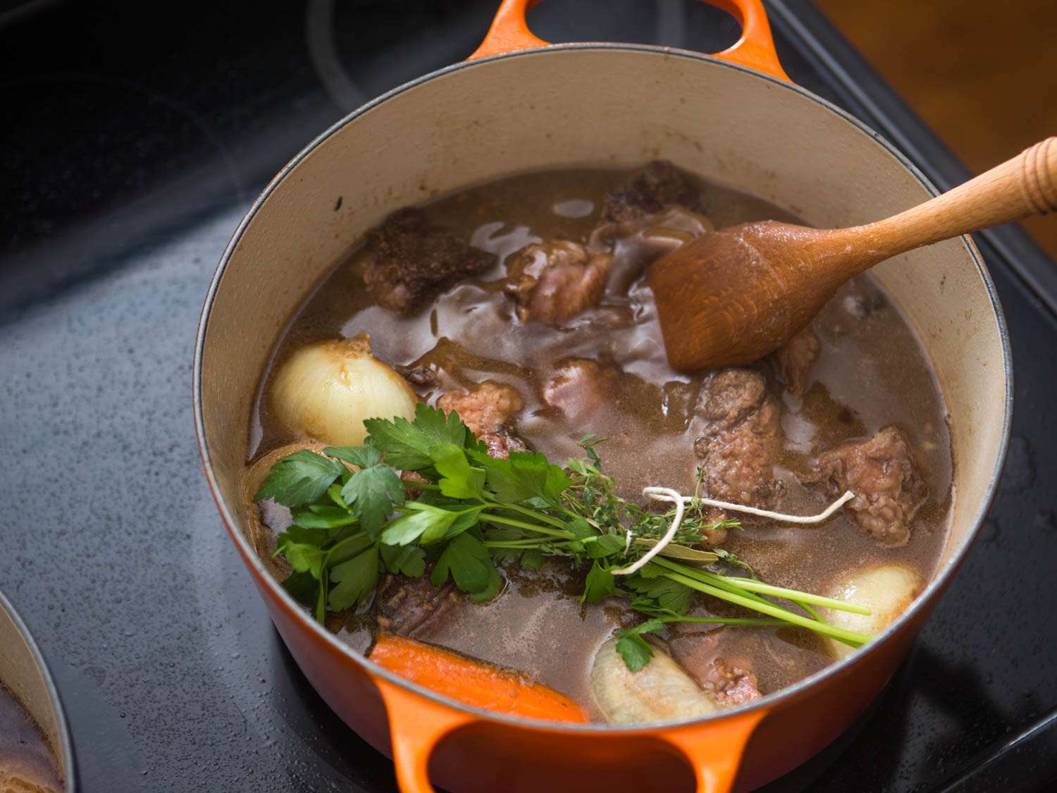 Bouquet garni bundled with twine laying on surface of simmering stew