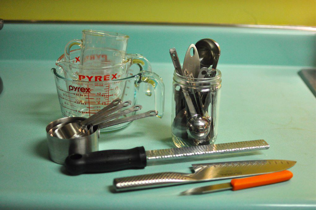 A counter holding a knife, a grater, and various measuring devices. 