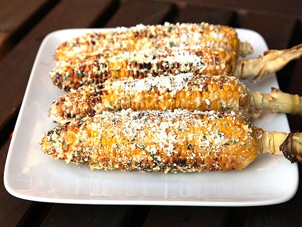 Four ears of homemade Mexican street corn on a white square platter.
