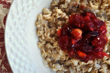Overhead closeup of Oatmeal with Cranberry Orange Hazelnut Compote, served in a shallow white bowl.