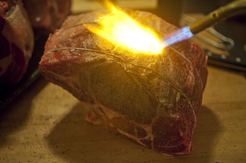 Torching the exterior of a large prime rib