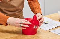 A person folds the top of the Chef'n Pop Top Microwave Popcorn Maker