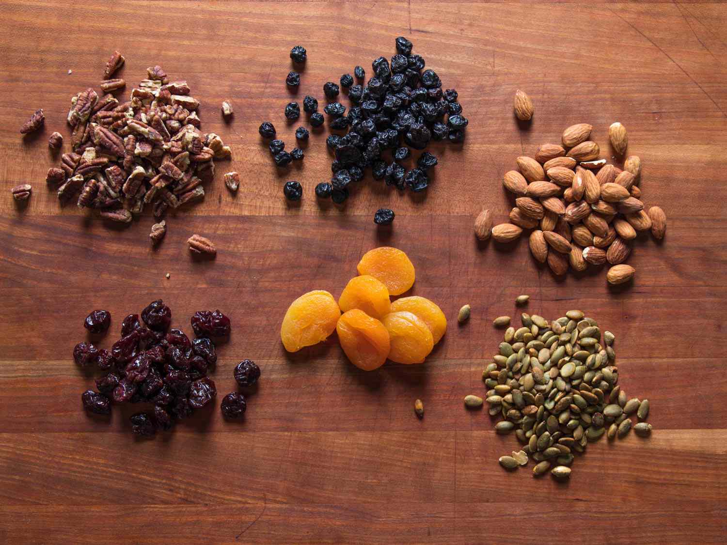 Dried seeds and fruits for homemade granola: pumpkin seeds, almonds, pecans, apricots, tart cherries, and blueberries.