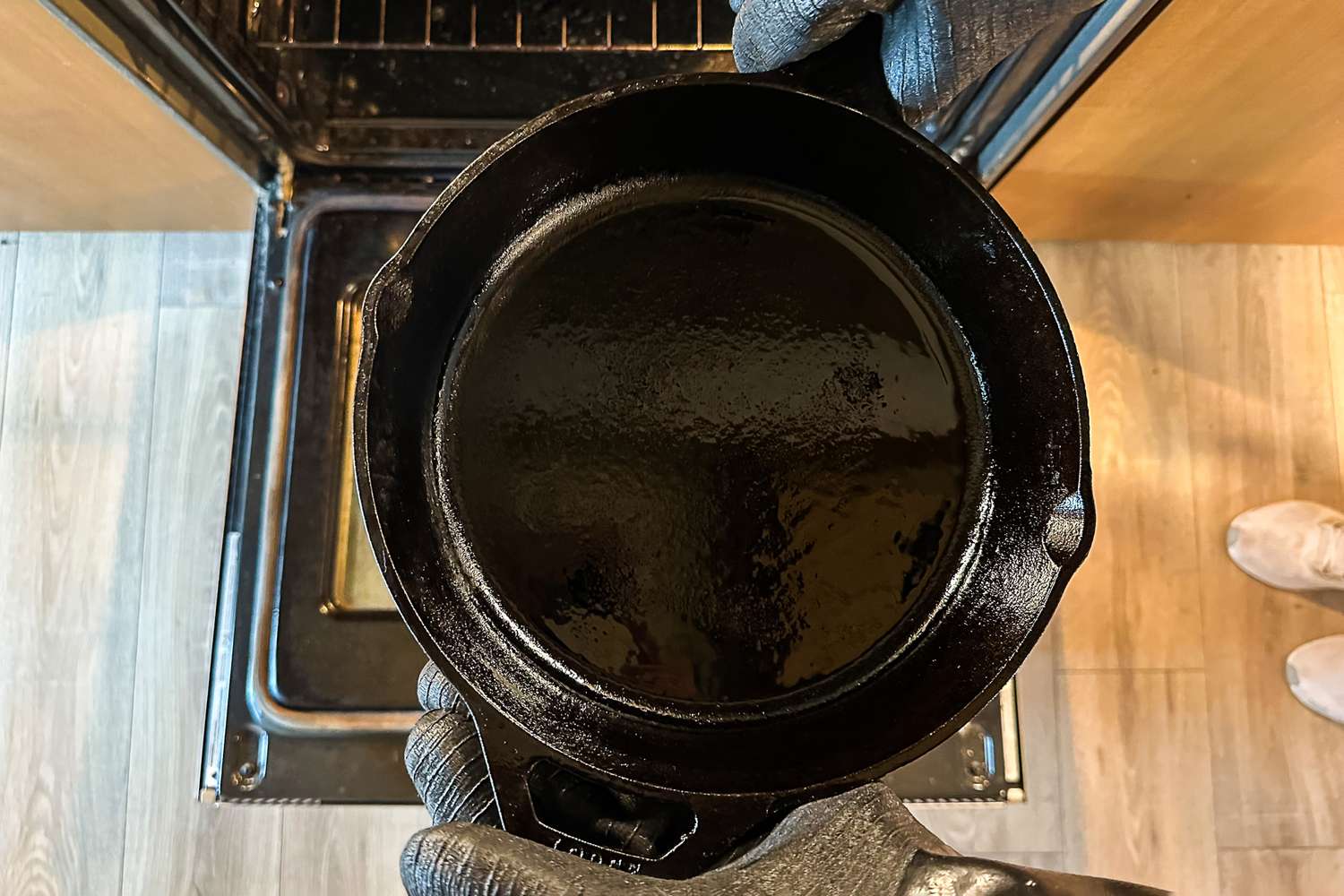 A person wears the Grill Armor Gloves BBQ Waterproof Gloves while holding a cast iron pan