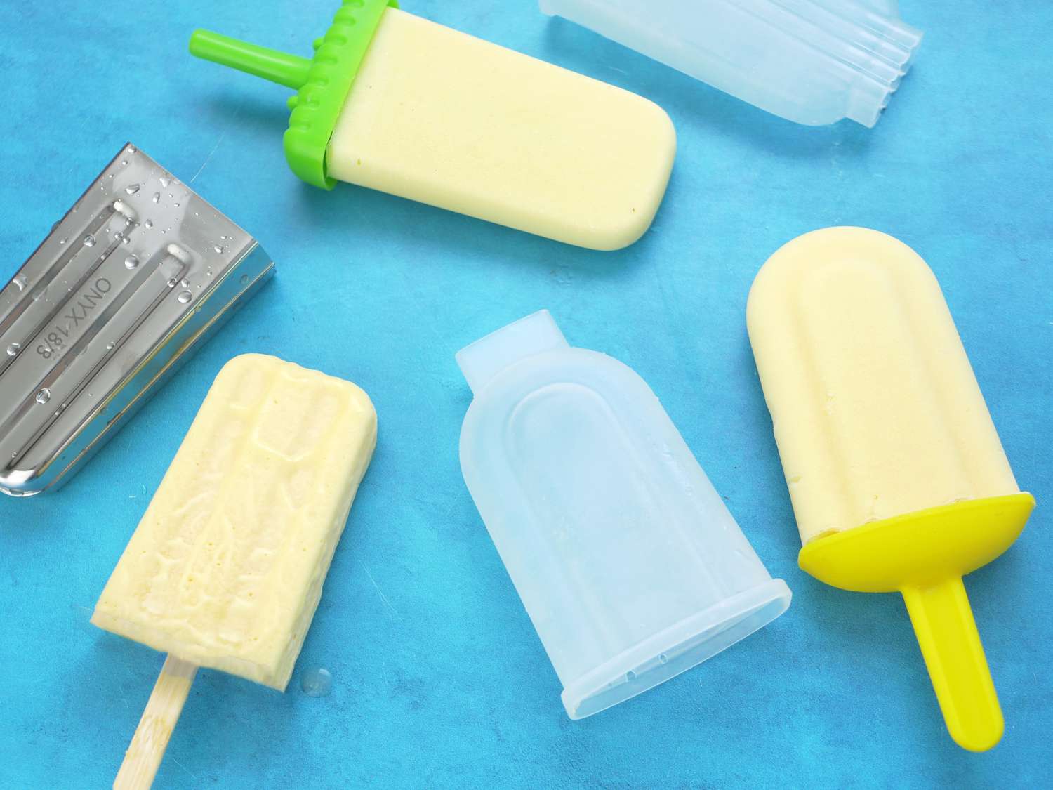 Assorted popsicle molds and ready popsicles placed on a blue surface