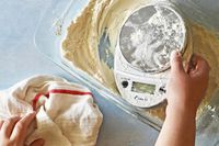 A person pulling the Escali out of a tub of flour.