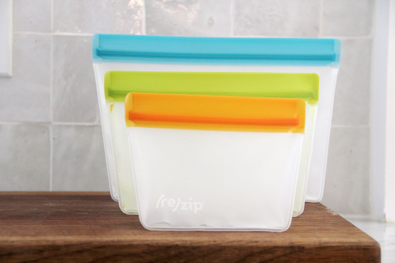 Reusable silicone storage bags with color-coded seals arranged on a wooden surface