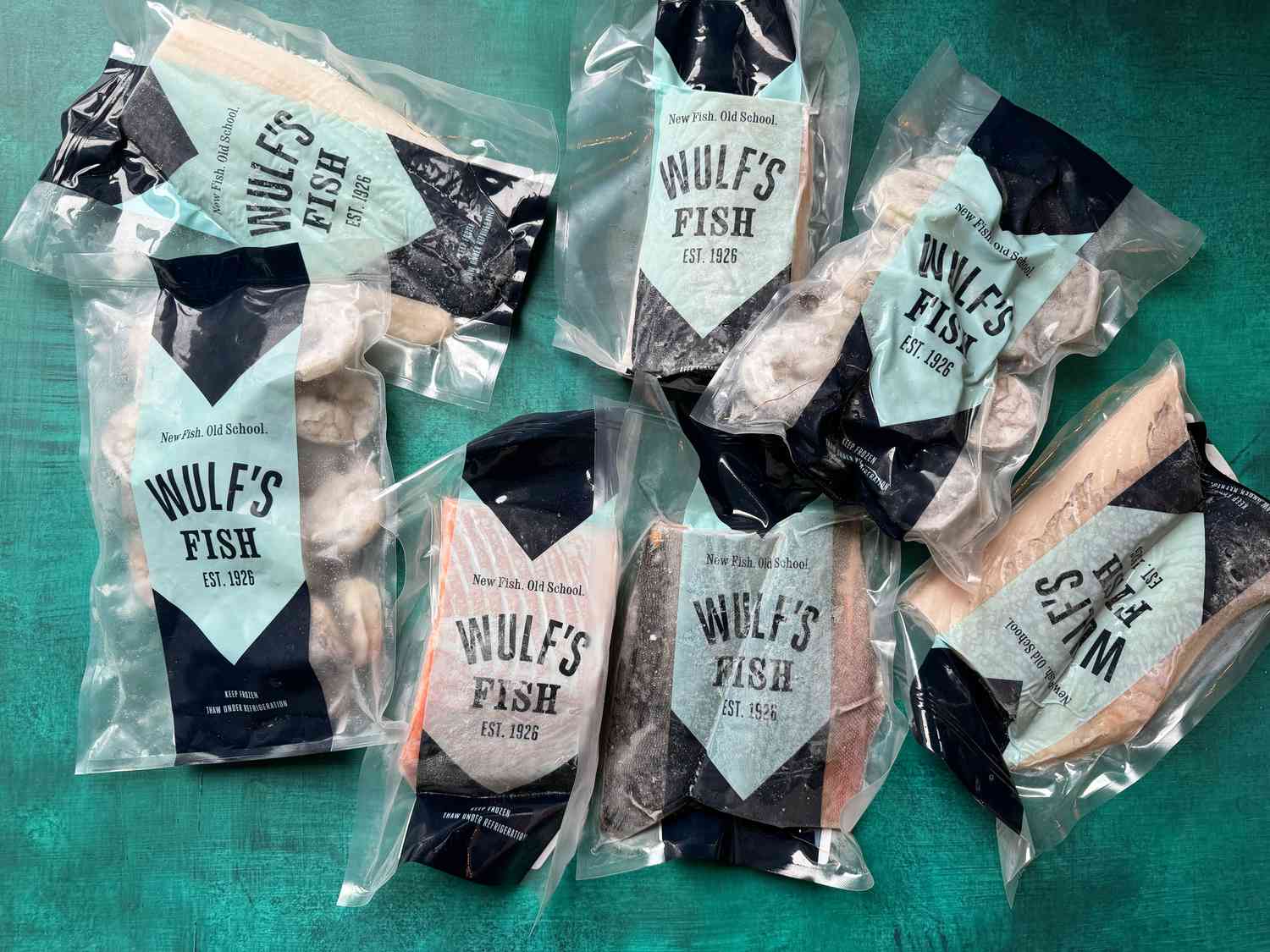 Various packages of frozen seafood laying a blue surface