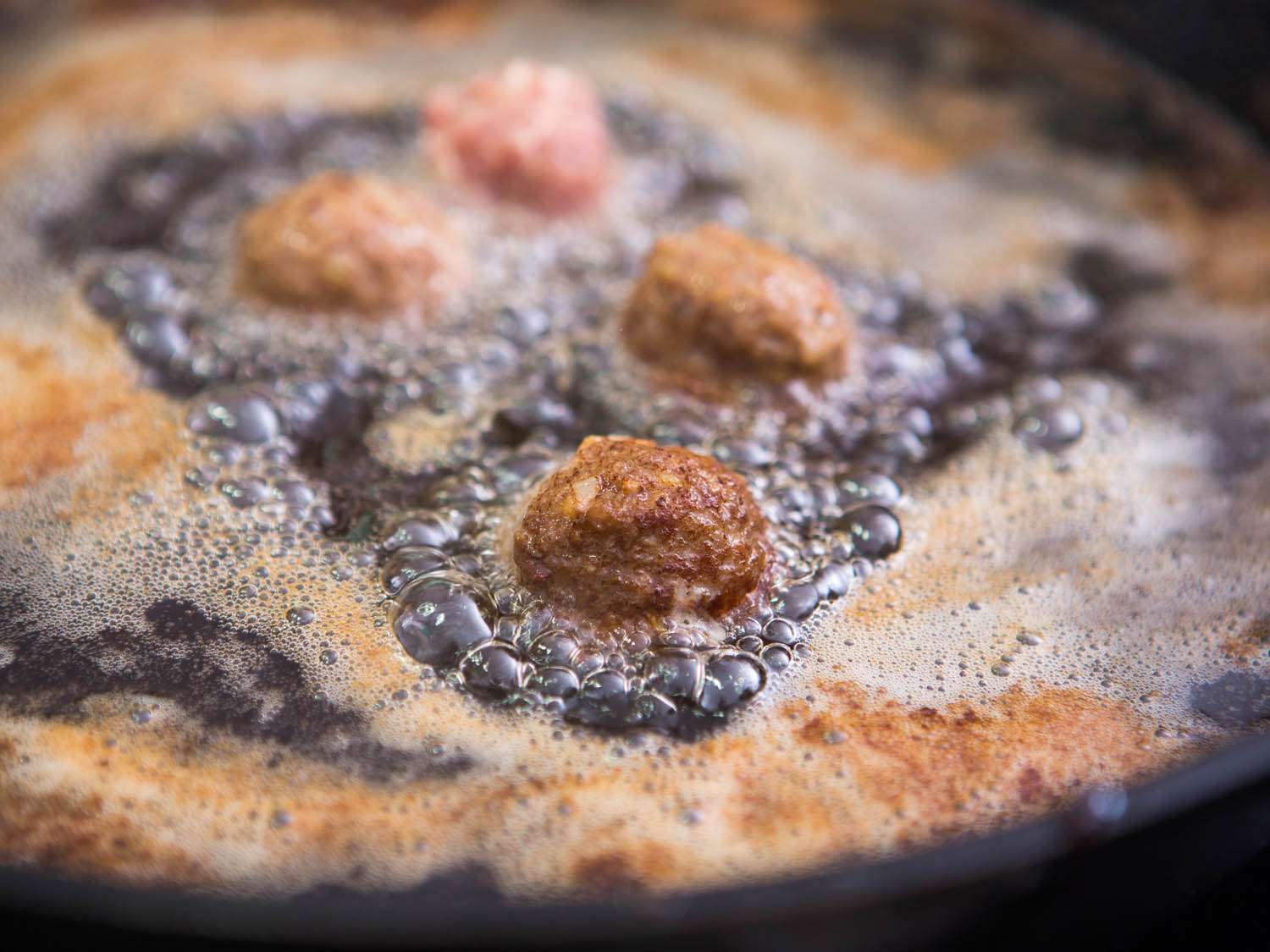 Swedish meatballs frying in oil.