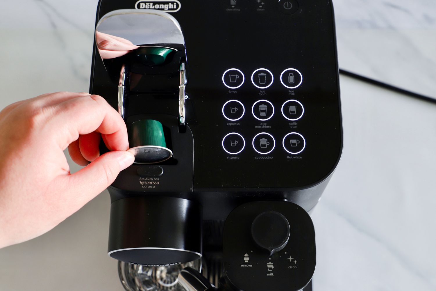 A person placing an espresso pod into the Nespresso Gran Lattissima Original Espresso Machine by De’Longhi