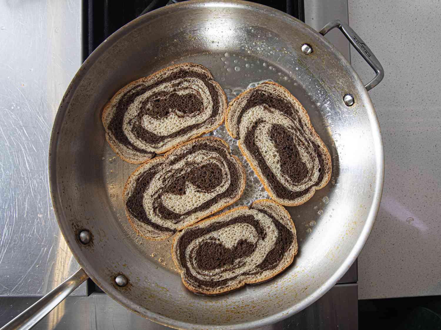 Four pieces of rye bread in a pan with butter