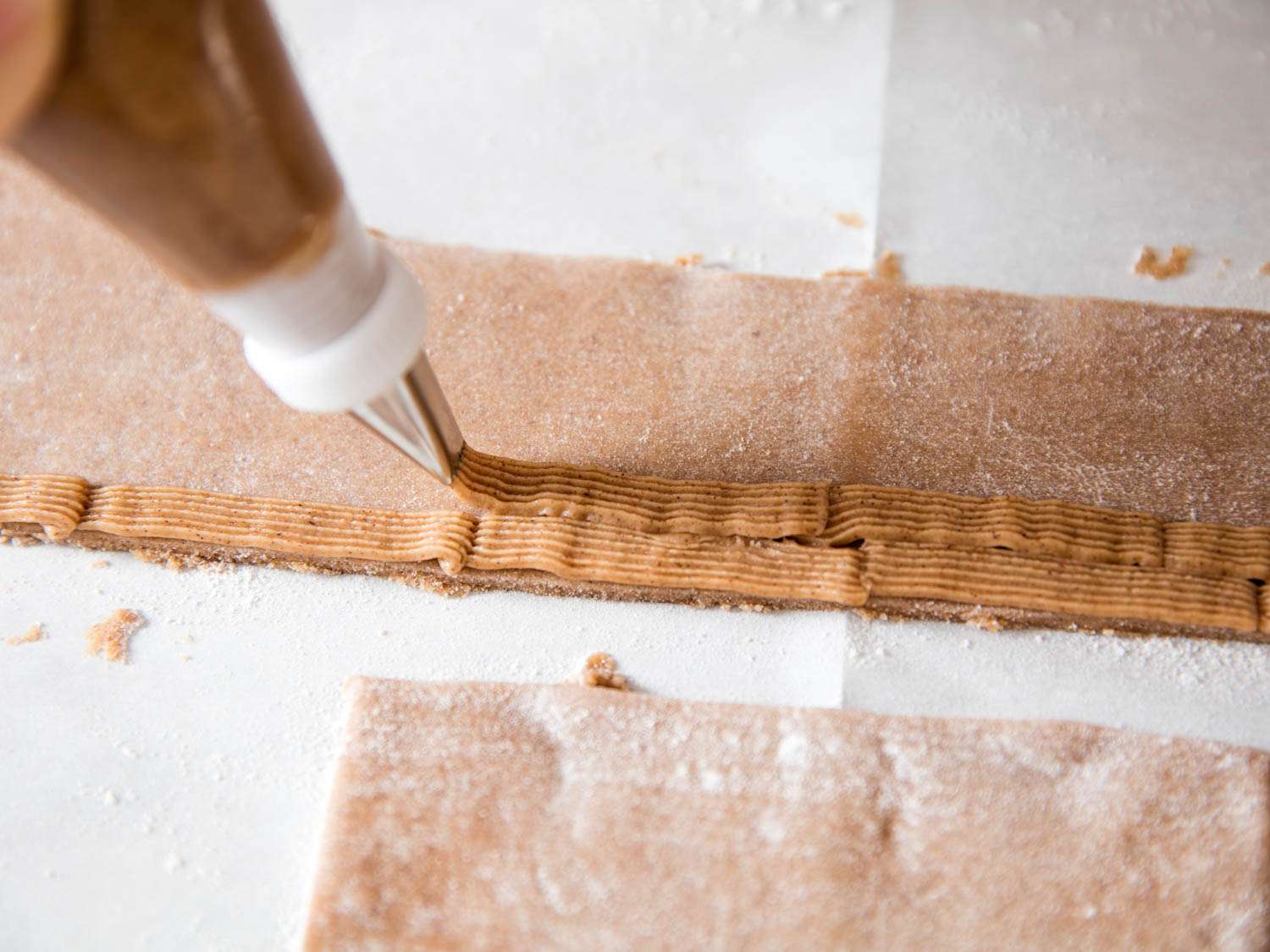 Piping the construction icing/cement onto some of the cut out gingerbread shapes.