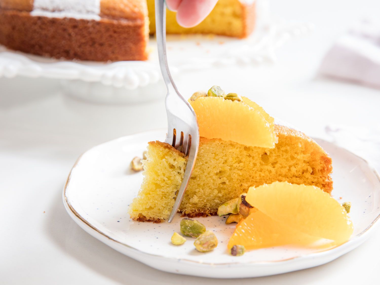 Digging into a slice of olive oil cake garnished with citrus segments